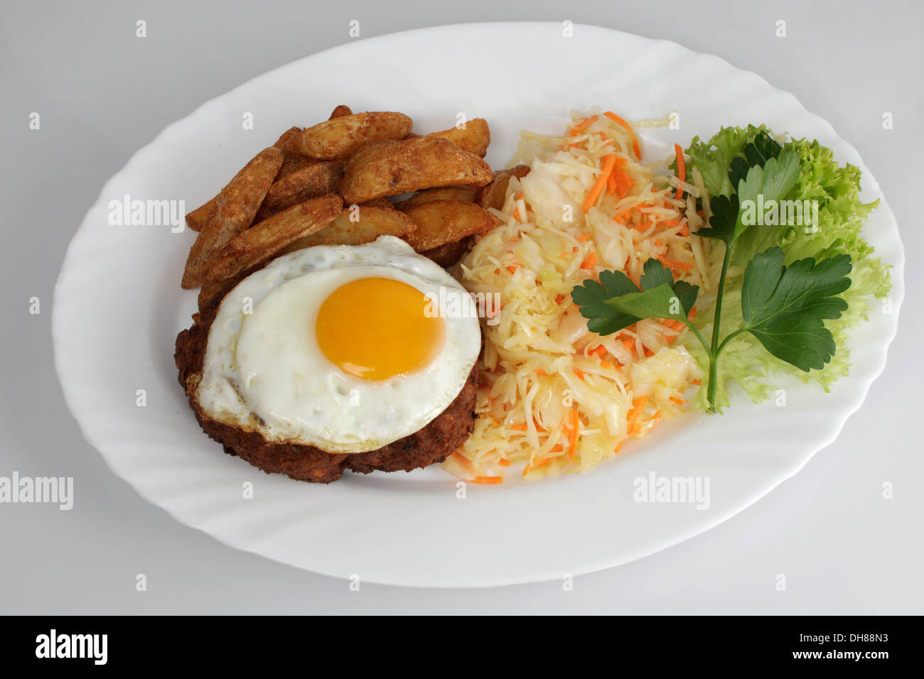 Farmers meat ball, hamburger steak, fried egg, baked potatoe wedges, coleslaw Stock Photo