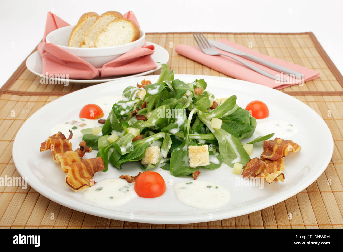 Field salad with potato dressing, bread croutons, fried bacon and French loaf Stock Photo