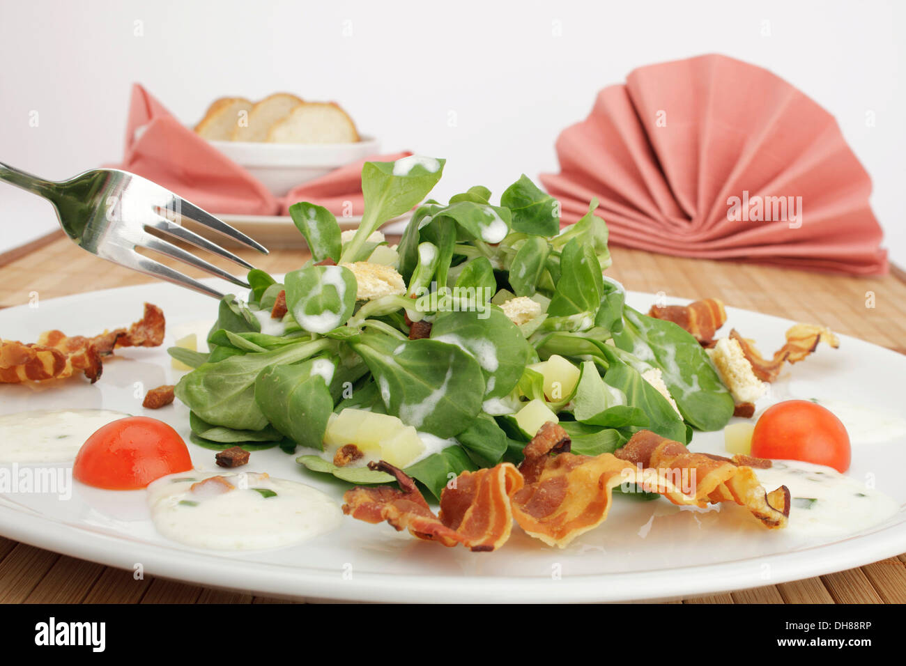 Field salad with potato dressing, bread croutons, fried bacon and French loaf Stock Photo