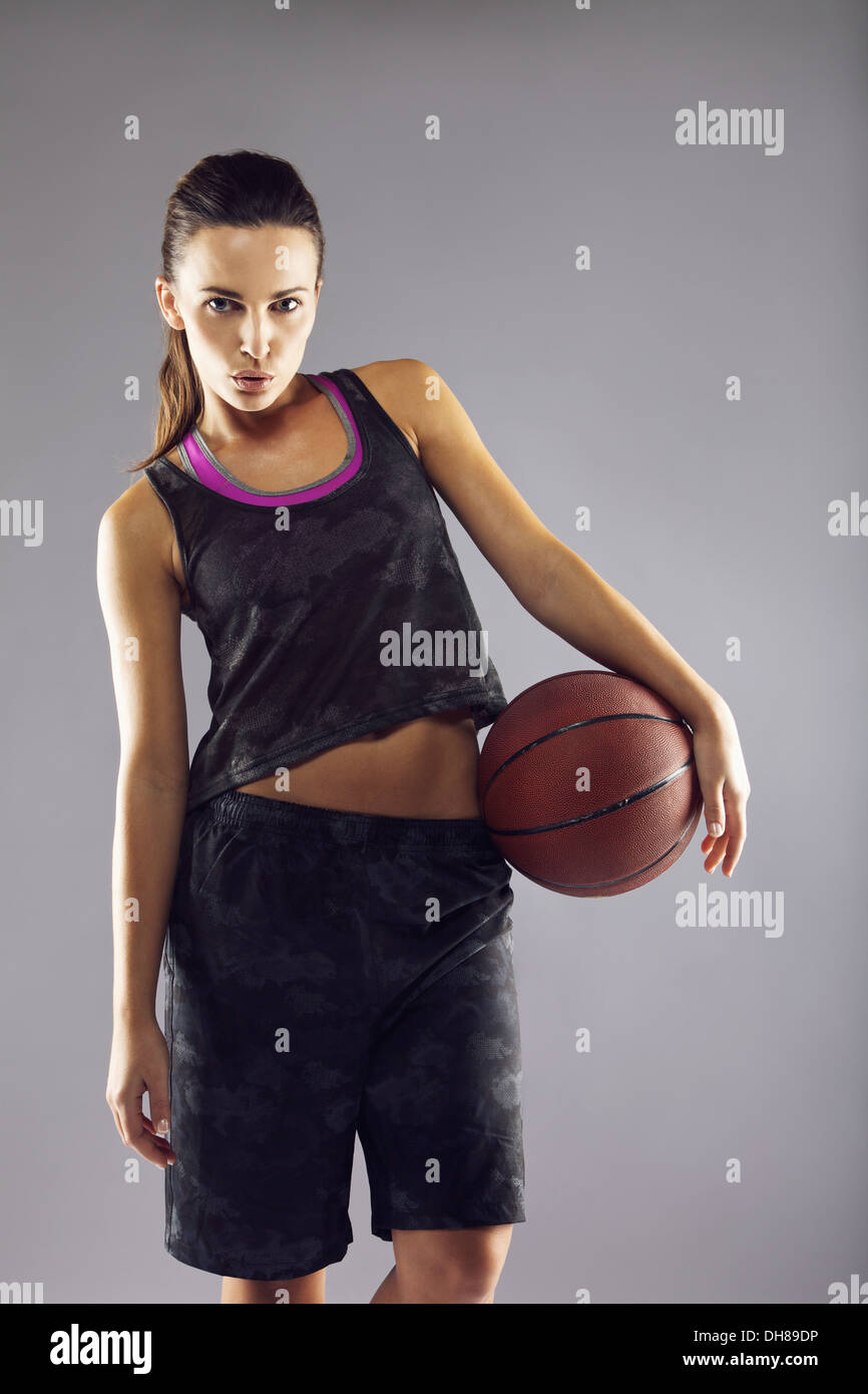 Portrait of beautiful young female basketball player in uniform with a