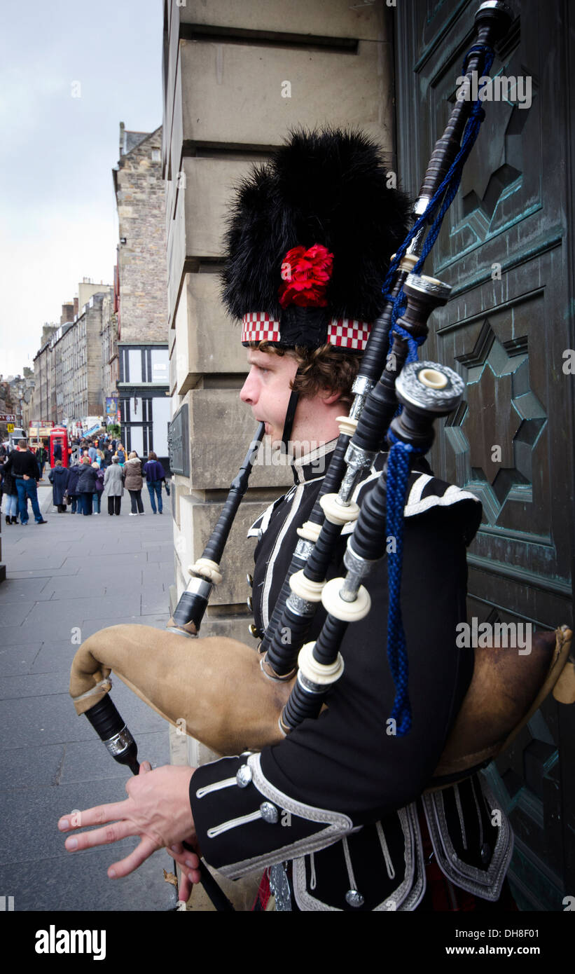 Piper in traditional costume playing bagpipes in front of grand door on