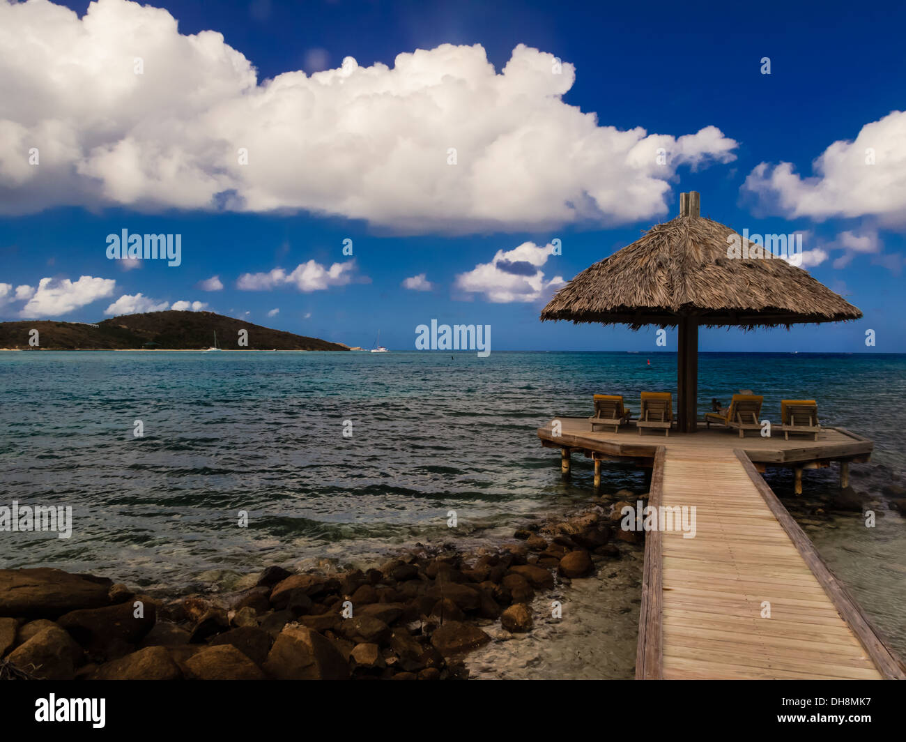 Private resort gazebo with thatched roof extends far into the turquoise water of the British Virgin Islands Stock Photo