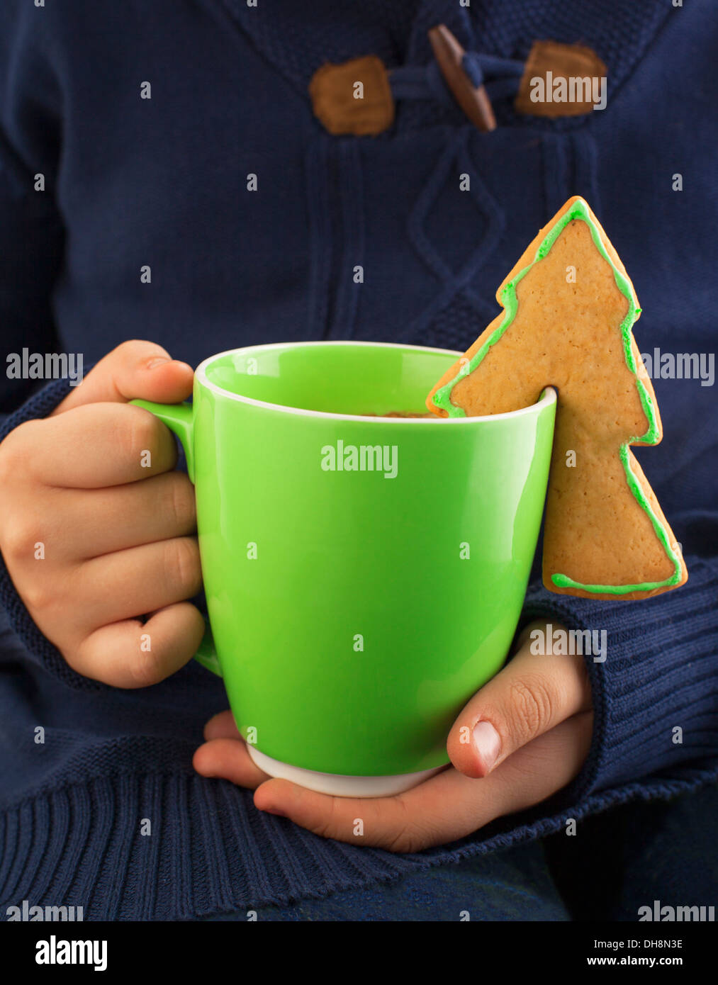 A closeup of a boy dipping a sugar cookie in hot chocolate with marshmallow Stock Photo