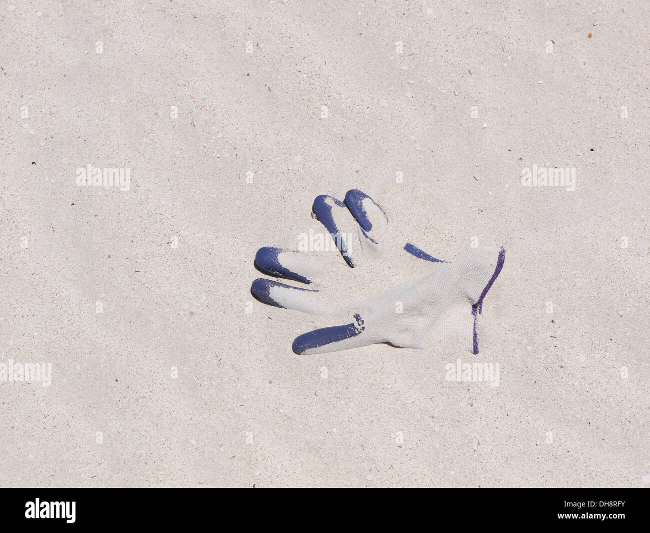 Lost glove partially covered in sand on a beach Stock Photo