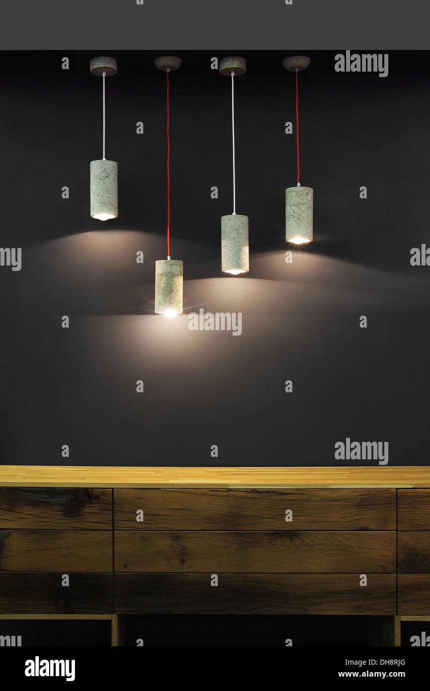 Four modern lamps above the wooden chest of drawers Stock Photo Alamy