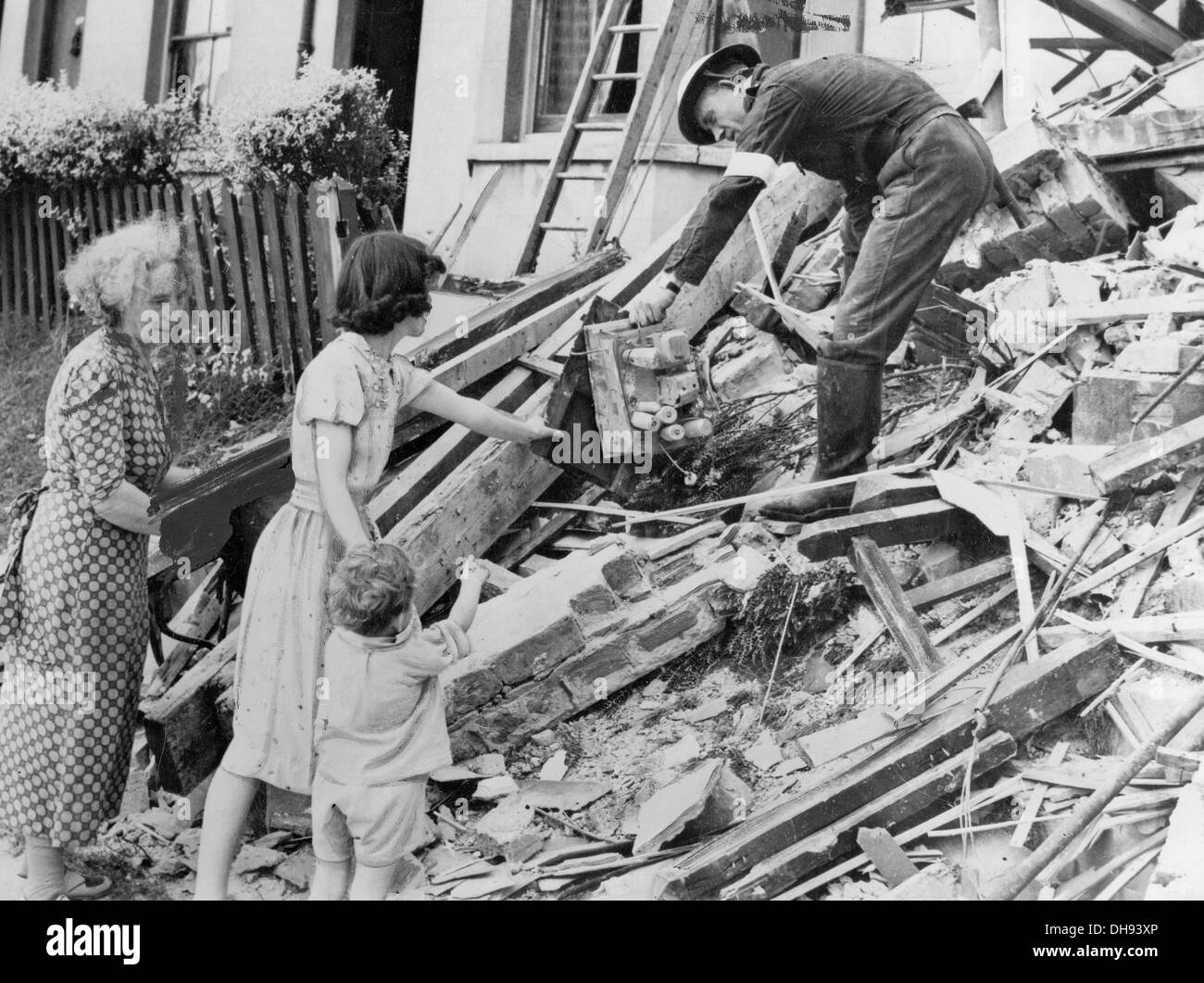 An ARP warden hands a damaged valve radio to a family after their home was hit by German bombs during the Blitz. Stock Photo