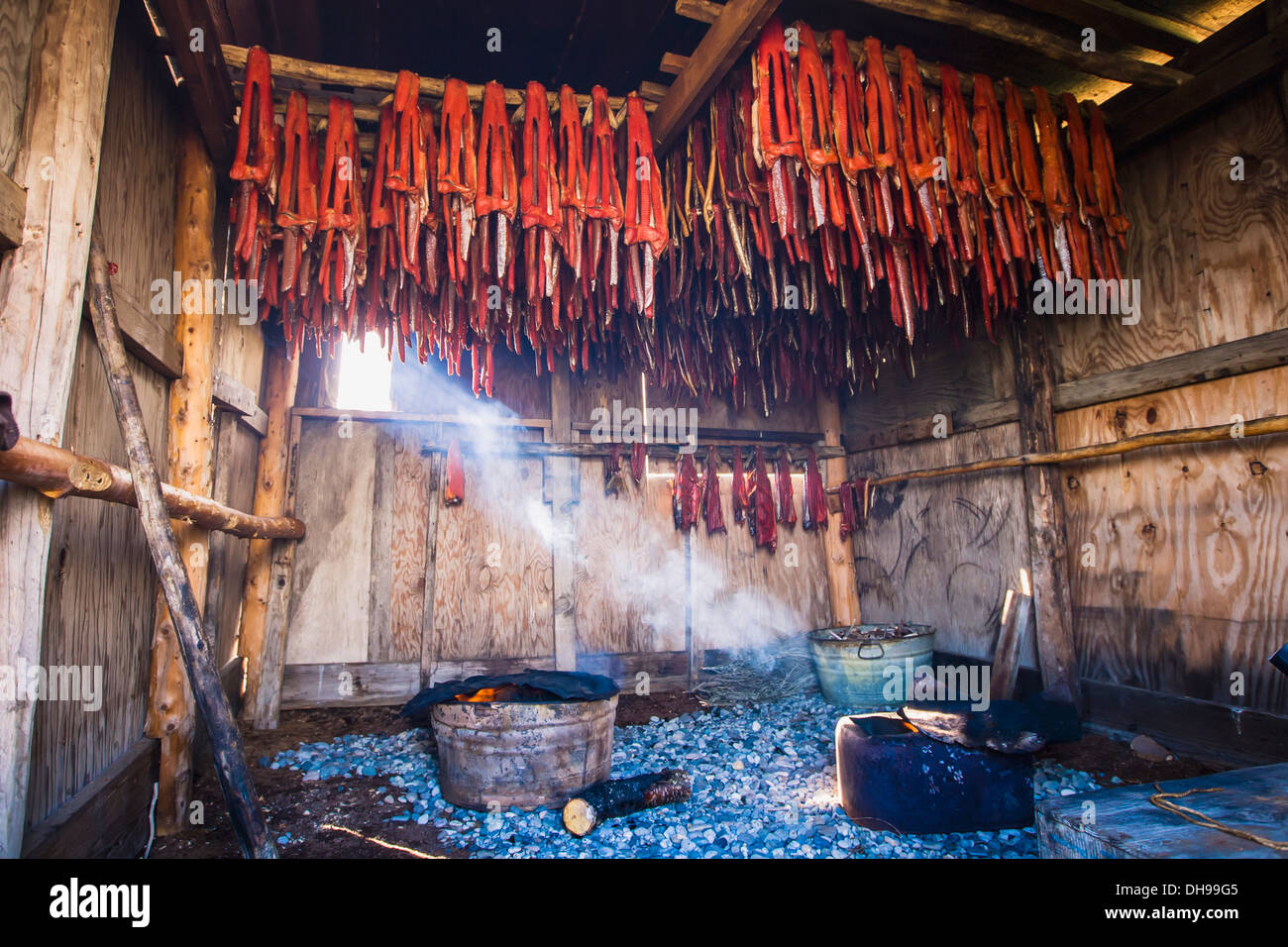 Strips Of Sockeye Salmon Hanging In A Large Smoker As A Shaft Of Light Streams In Showing The Smoke From The Fires. Alaska Stock Photo