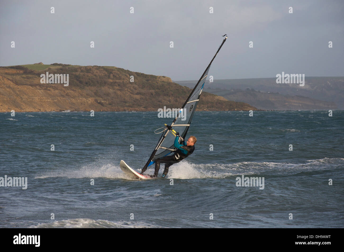 Water sports. Windsurfing man, wearing a wetsuit, speeding over the