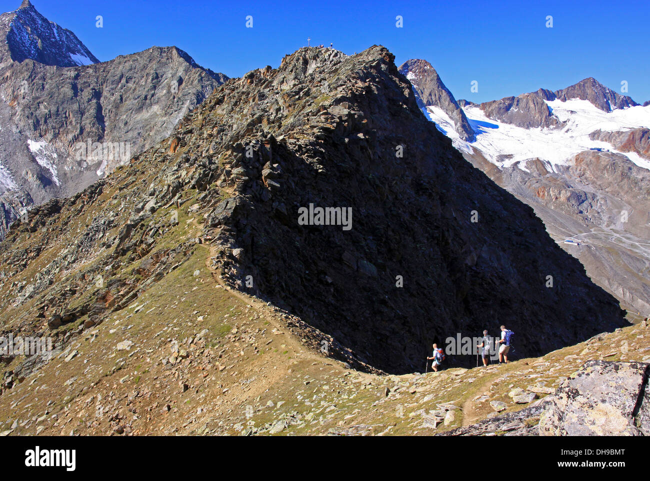Three mountain walkers hiking over mountain ridge in the mountains of the Alps Stock Photo