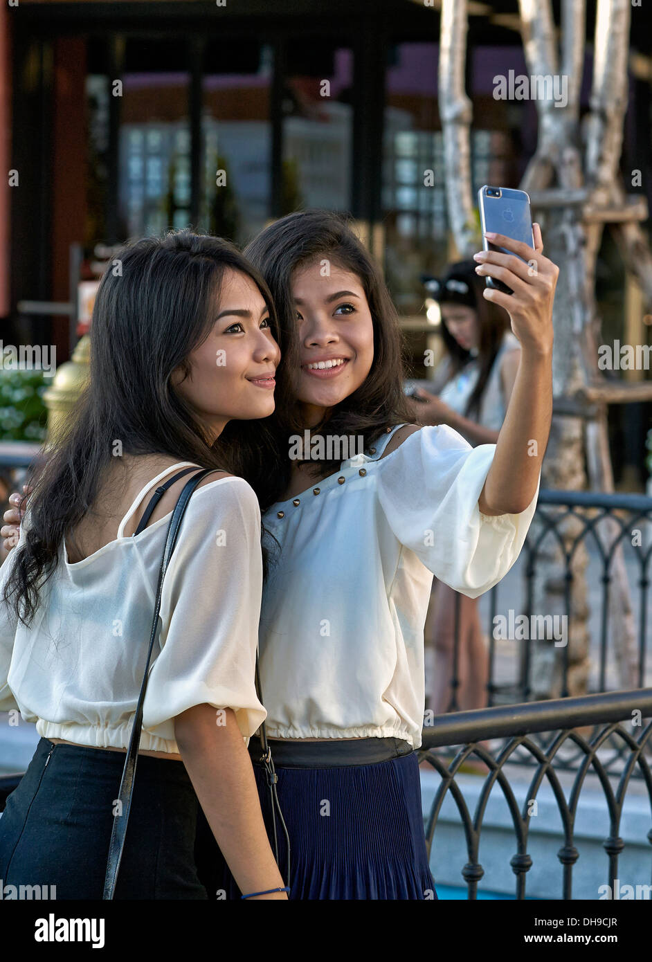 Selfie girls. Asian teenagers using a camera phone to take a self portrait known as a 'selfie'. Thailand S. E. Asia. Stock Photo