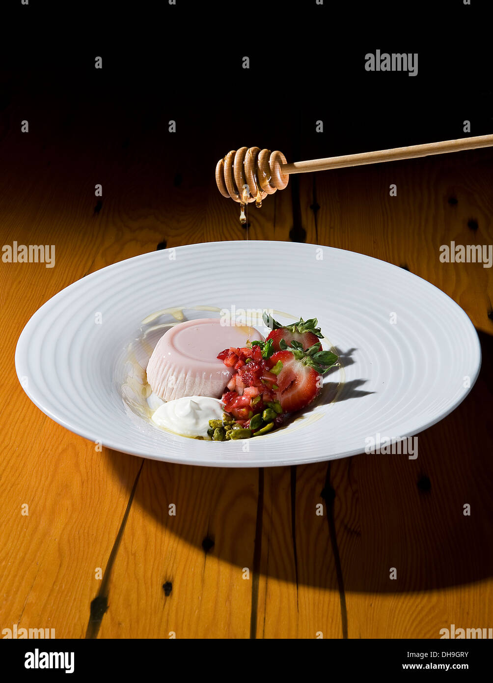 Strawberry Panna Cotta with honey being drizzled on top. Stock Photo
