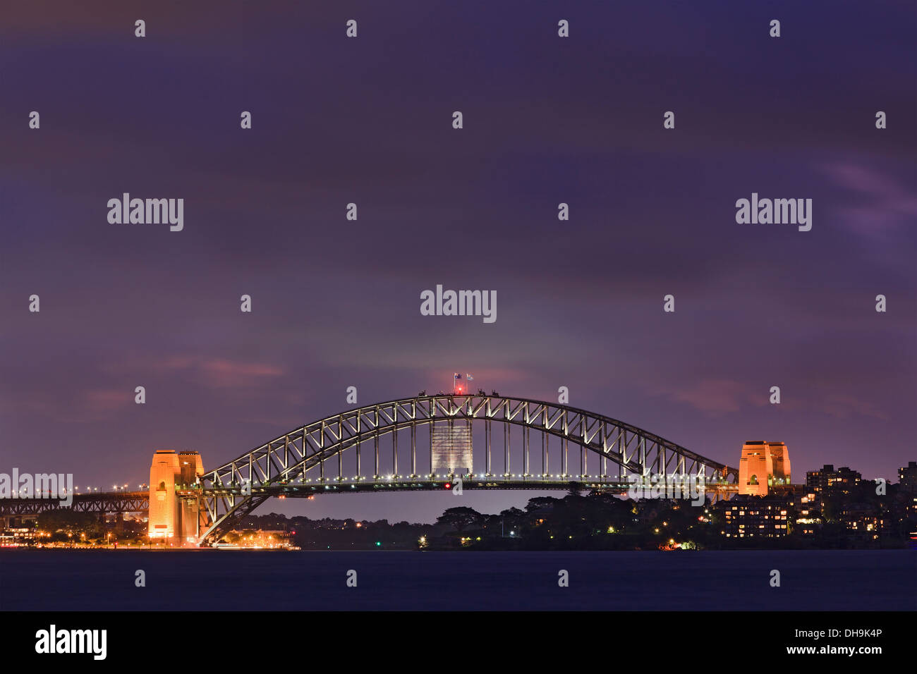 Sydney city Harbour bridge side view at sunset illuminated with lights cloudy dark sky panoramic side view Stock Photo