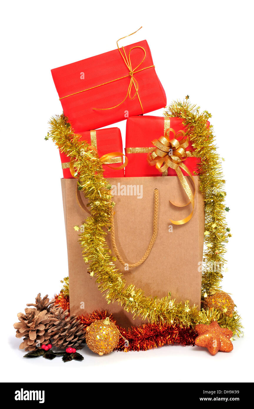 some christmas gifts wrapped with red wrapping paper and with a golden ribbon, in a shopping bag, and christmas ornaments on a w Stock Photo