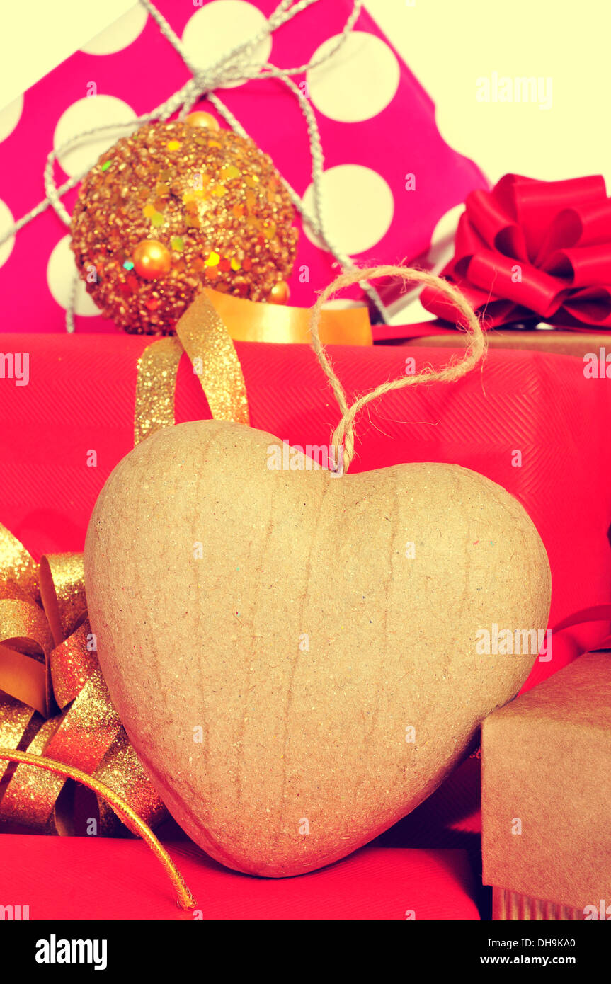 closeup a heart-shaped ornament and some christmas gifts wrapped with wrapping paper of different colors and ribbon bows, with a Stock Photo