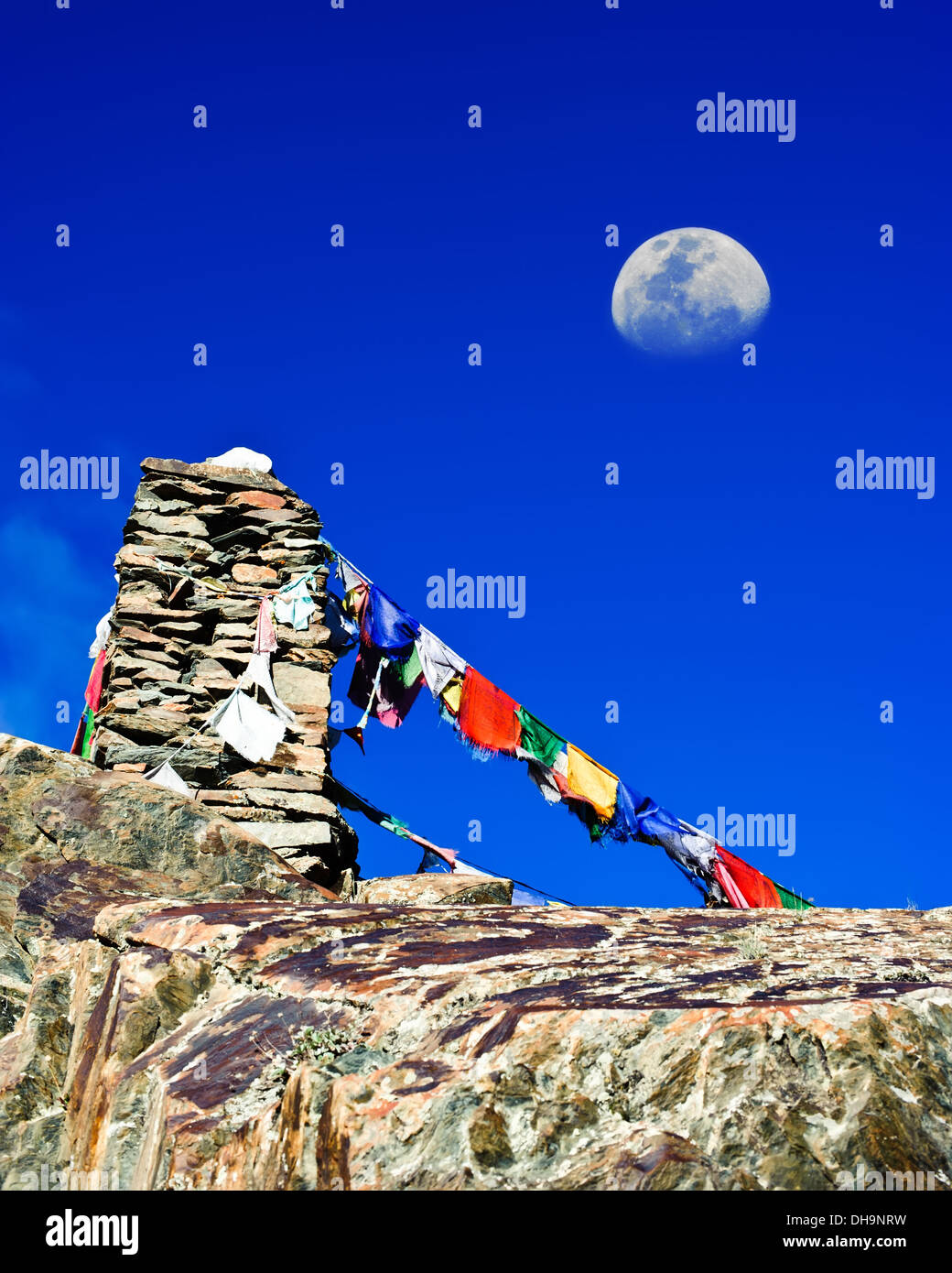 Buddhist stone tower praying flags and moon at Himalaya high mountain road pass at Manali - Leh highway over blue sky India Stock Photo