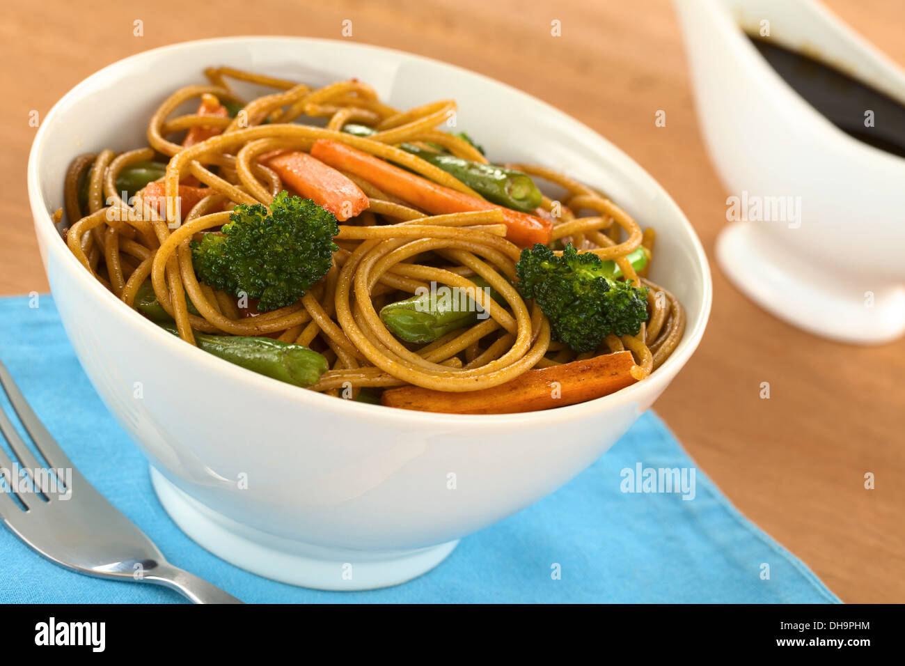 Vegetable and wholewheat spaghetti stir fry in white bowl with soy