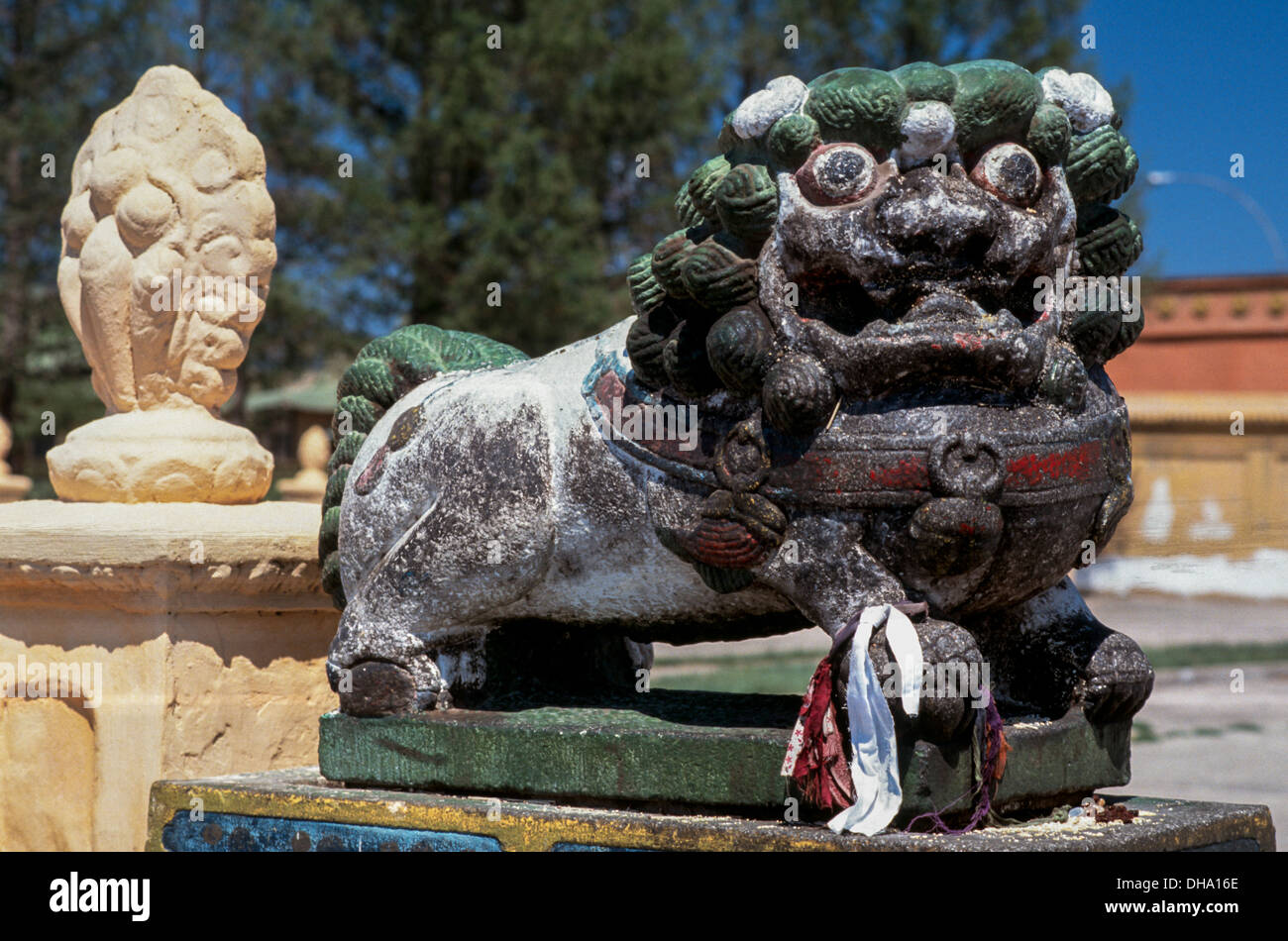 A majestic stone snow lion with green mane guards the entrance to the