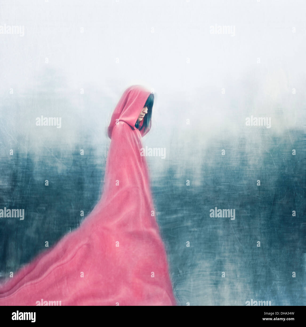 Woman wearing red cape walking outdoors Stock Photo