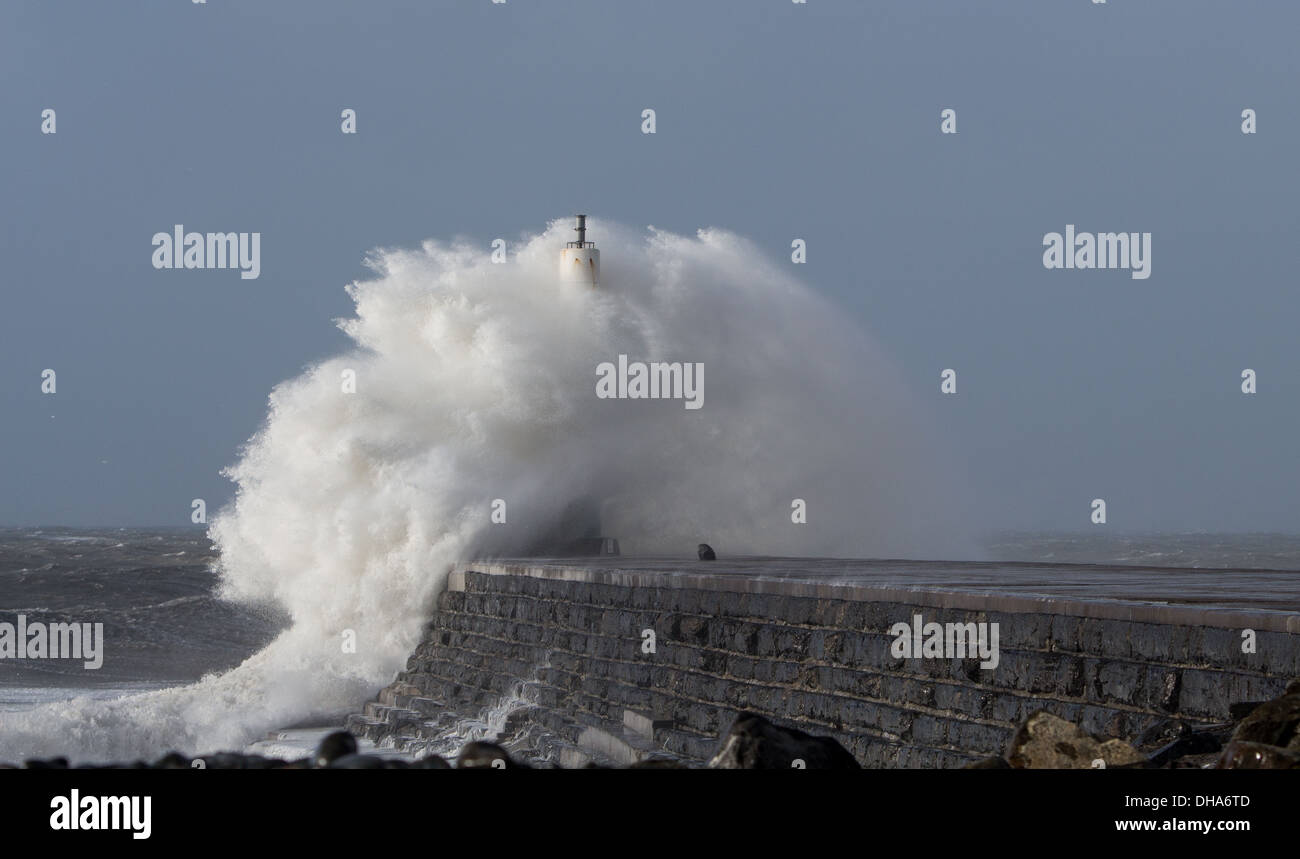 A huge wave crashes over the lighthouse, at high tide, in Aberystwyth during high winds & a storm Stock Photo
