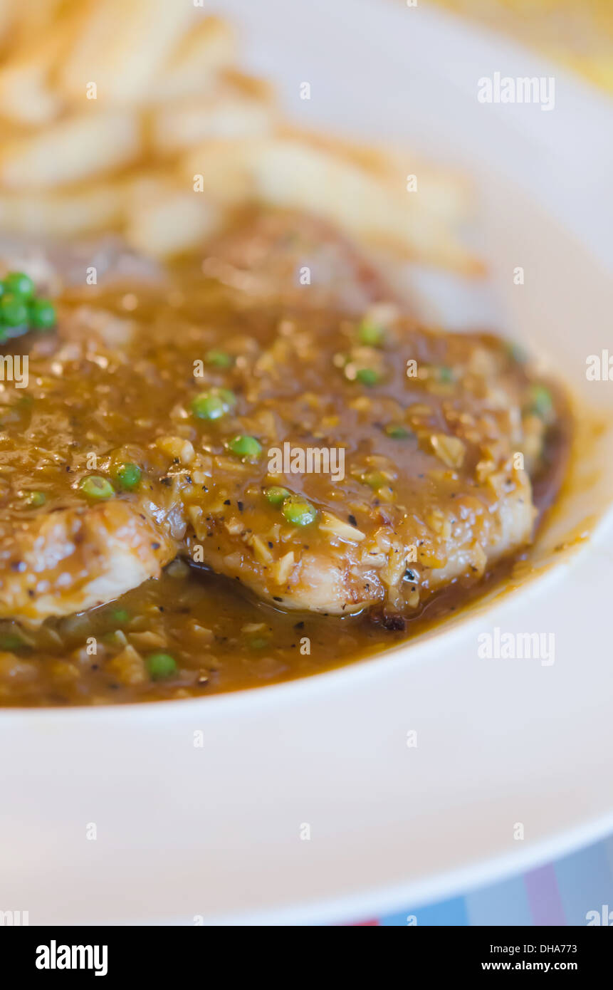 close up beef steak with green peppercorn sauce served with chips and