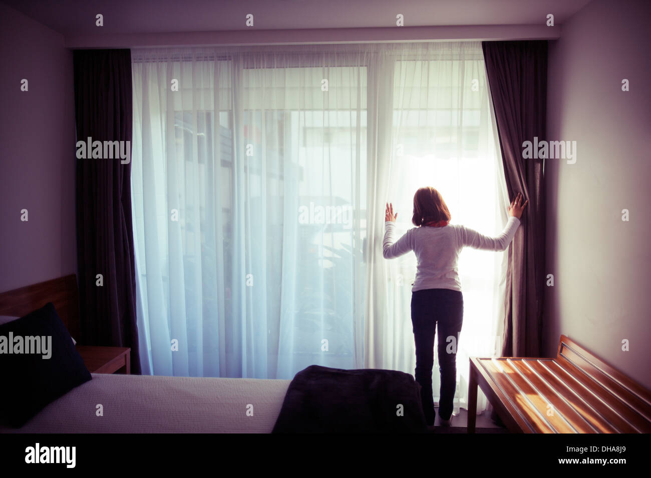 Woman looks out of bedroom glass doors Stock Photo