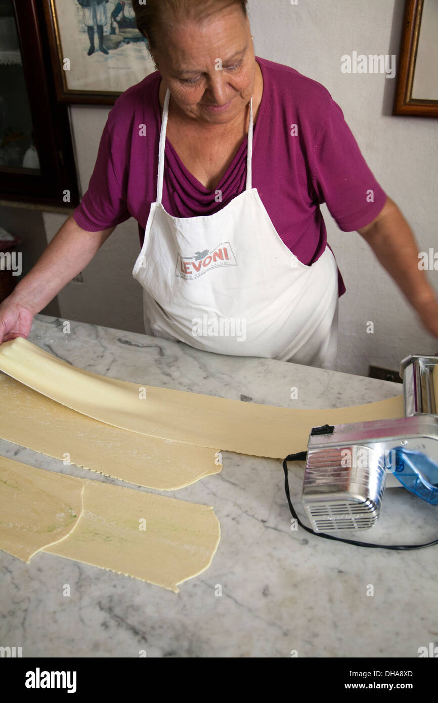 Woman Preparing Pasta Dough Rolling out Through Machine Stock Photo