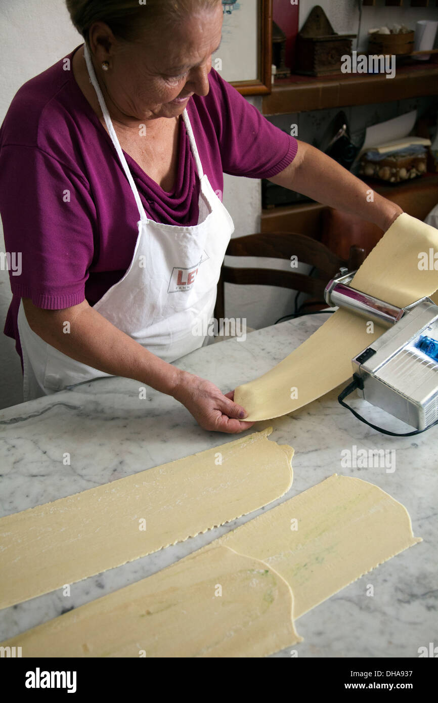 Woman Preparing Pasta Dough Rolling out Through Machine Stock Photo