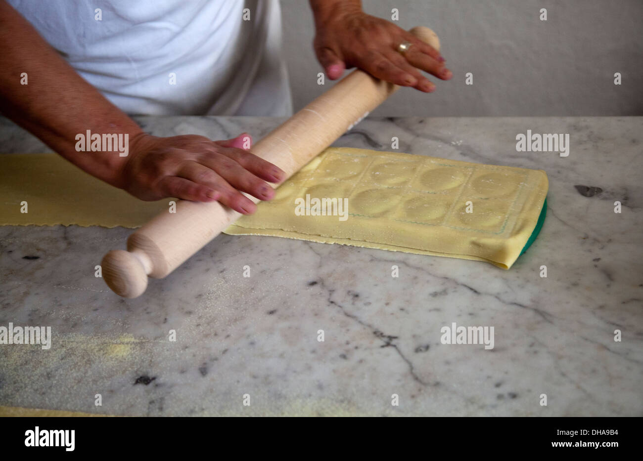 Woman Preparing Pasta Dough And Rolling Over Ravioli Tray, with filling Stock Photo