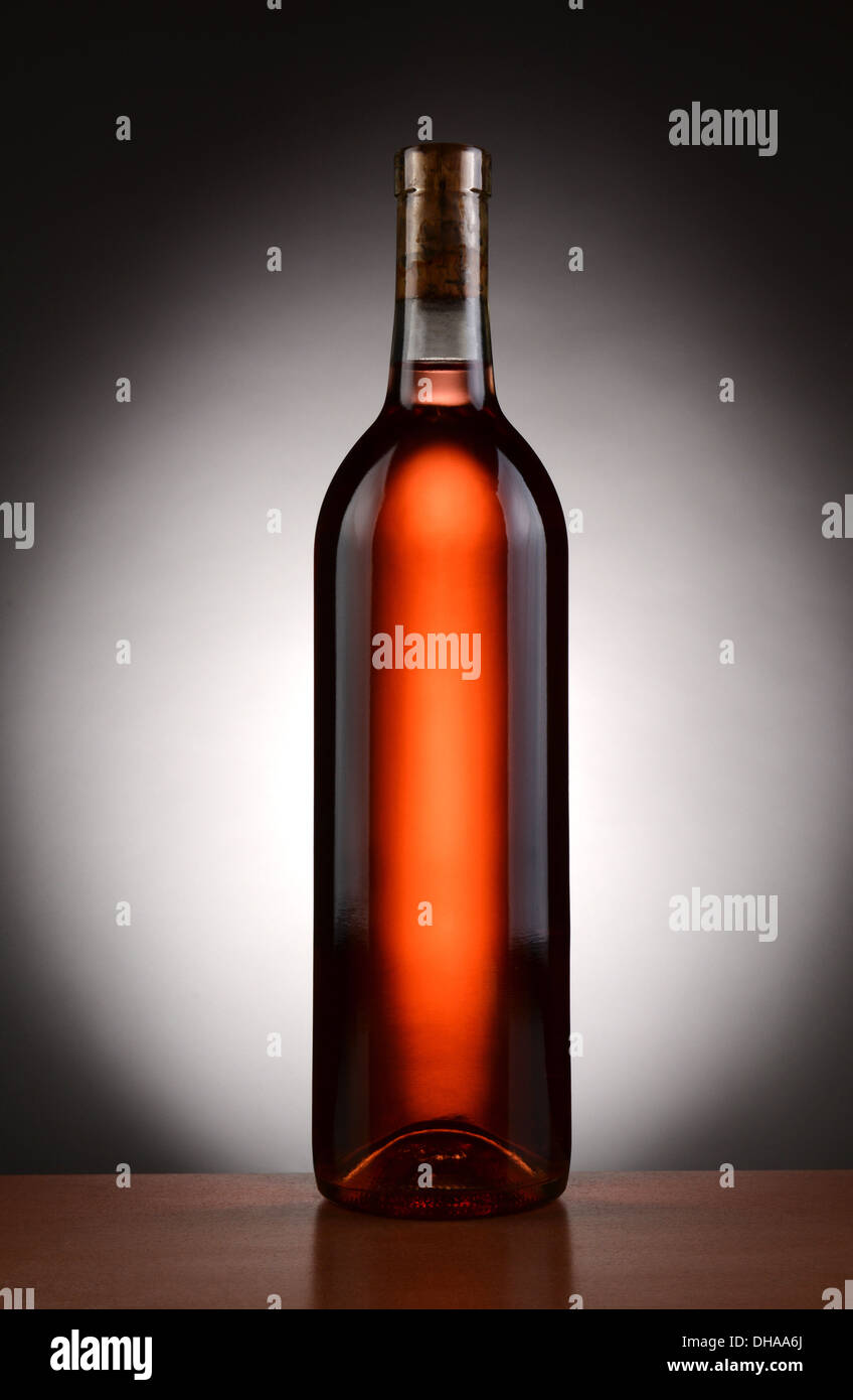 A blush wine bottle backlit with a light to dark spot background. Vertical format. Stock Photo