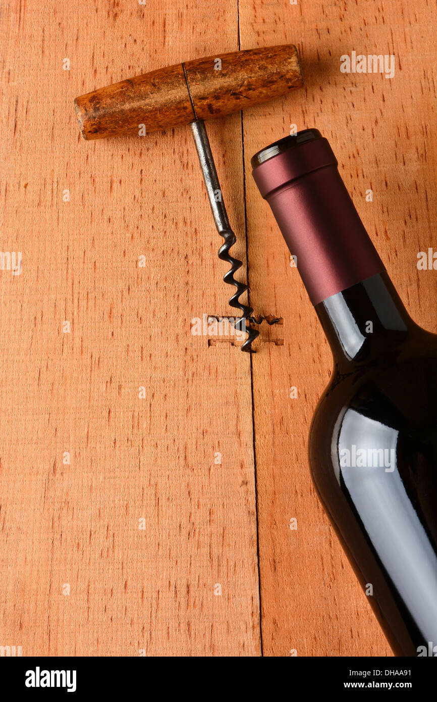 Cabernet bottle and corkscrew on a rustic wooden surface. The antique opener and bottle are at an angle Stock Photo