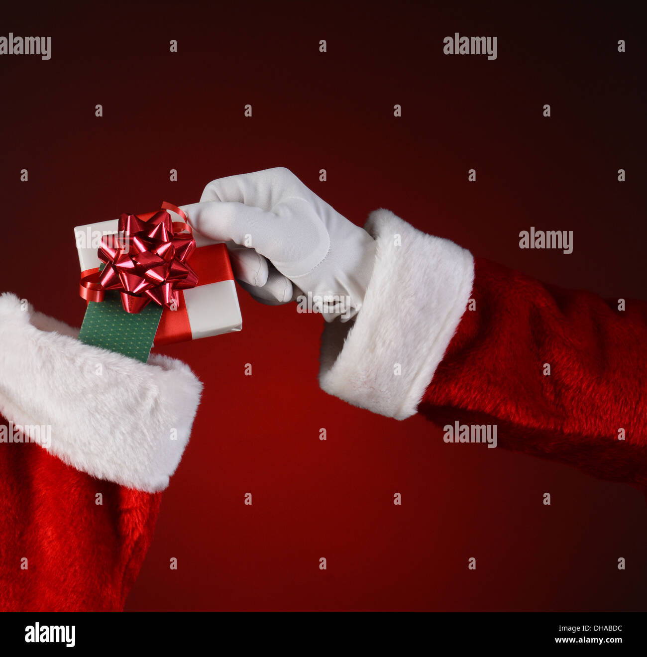 Closeup of Santa Claus placing a small wrapped present into a holiday stocking. Stock Photo