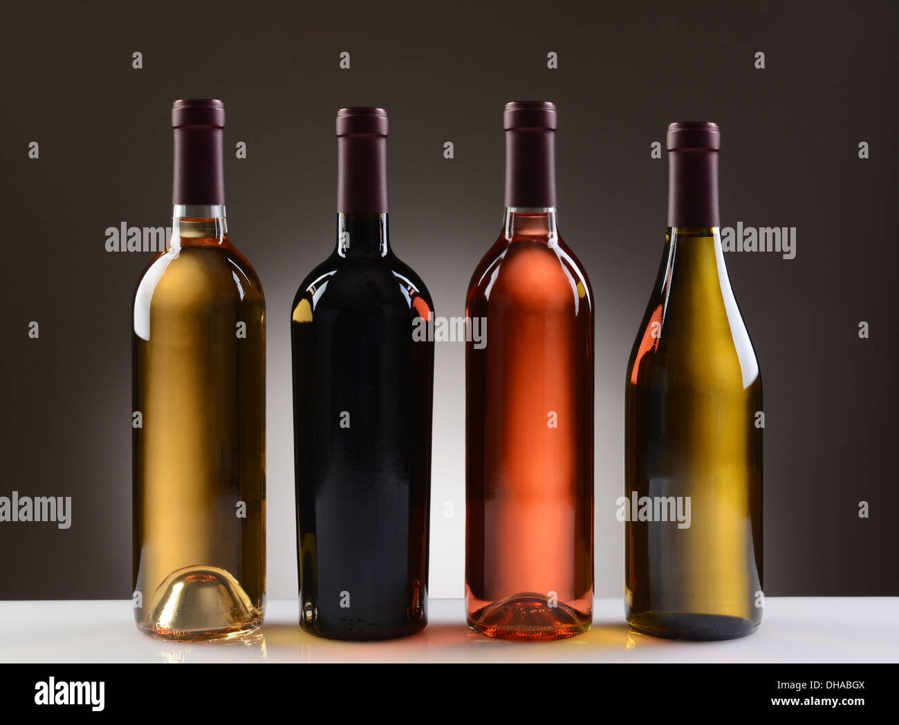 Four Wine Bottles with no labels on a light to dark gray background. Stock Photo