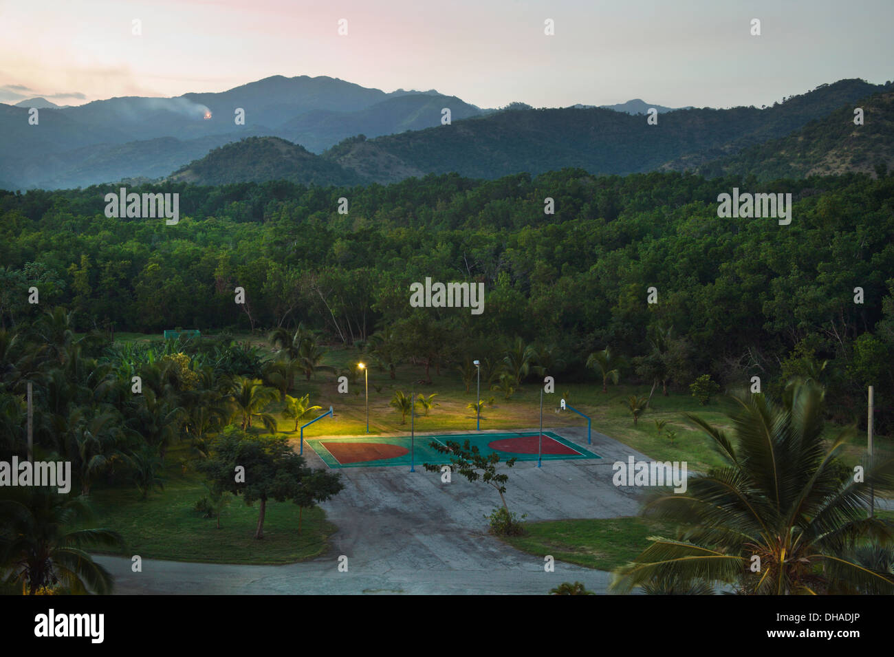 Basketball Court Illuminated With Lights At Dusk With Mountains In The