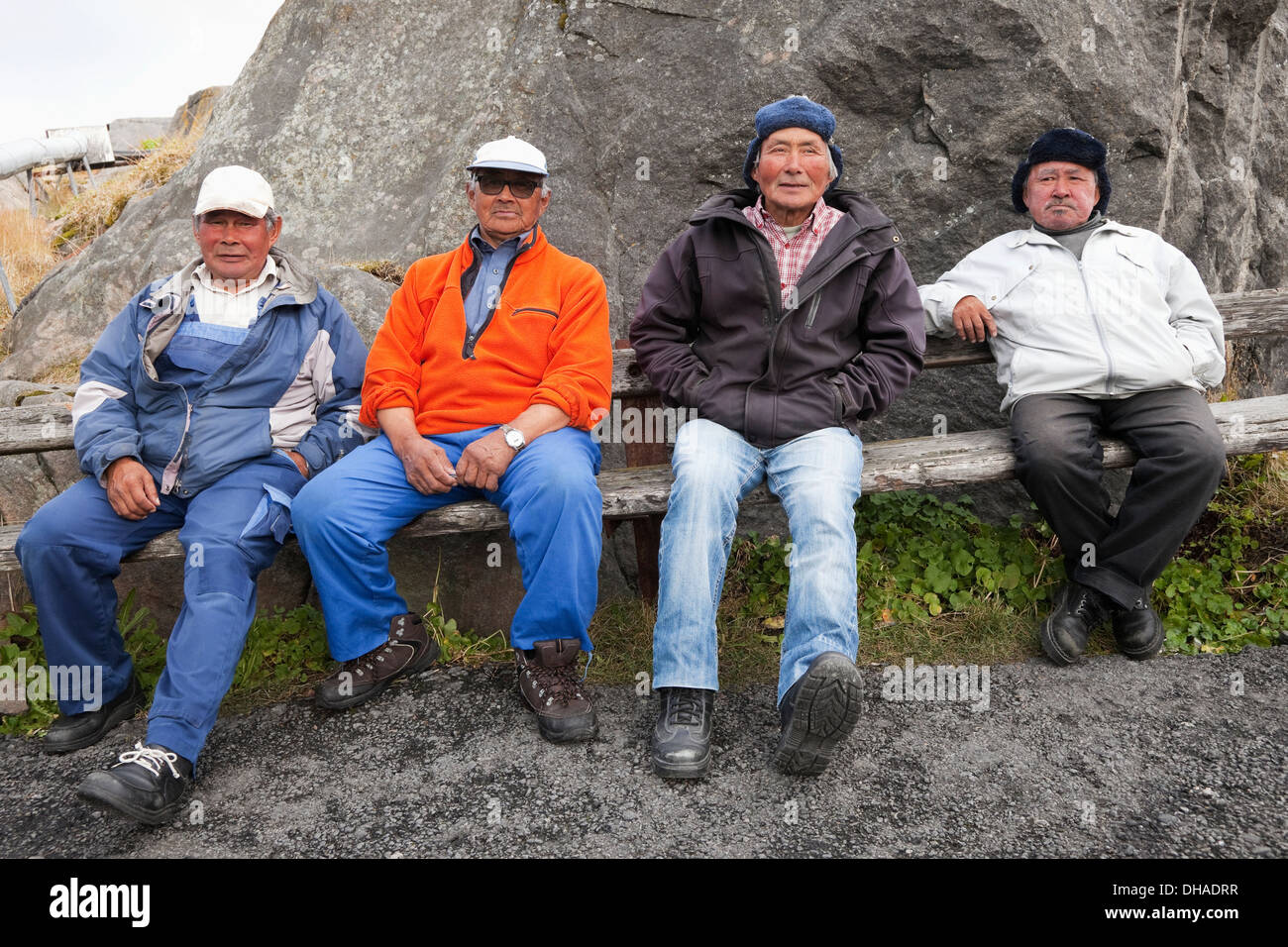 Four Inuit Men Sitting On A Bench In A Village; Kangaamiut, Greenland Stock Photo