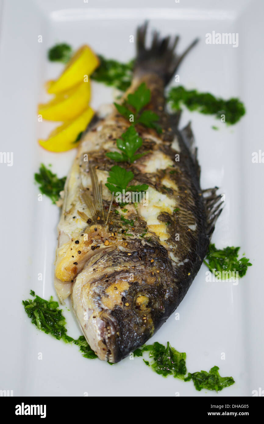 grilled sea bass with pesto, parsley and a slice of lemon Stock Photo