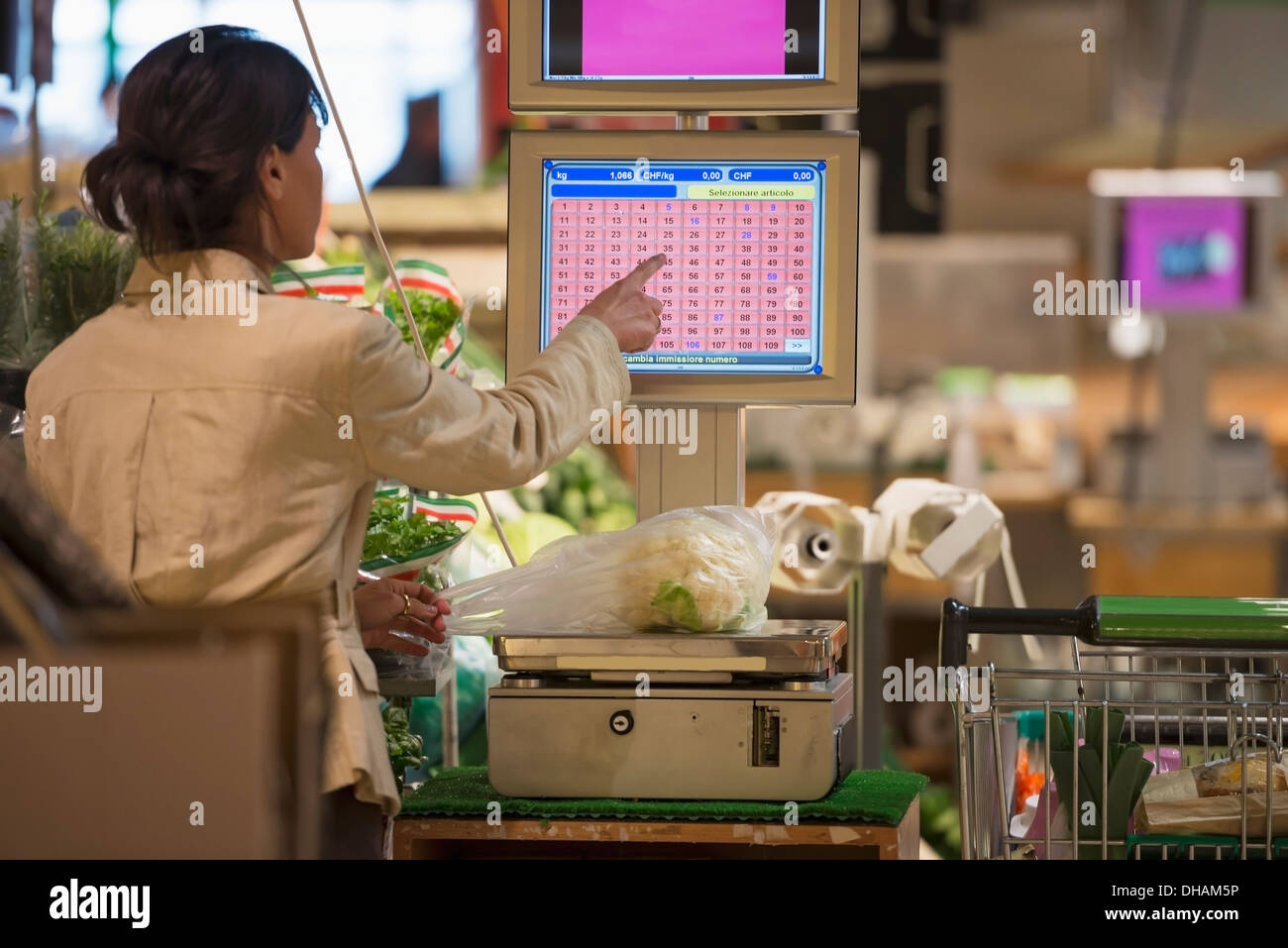 A Cashier Weighs Fresh Produce On A Scale And Chooses A Button On The Screen At Checkout; Ascona, Ticino, Switzerland Stock Photo