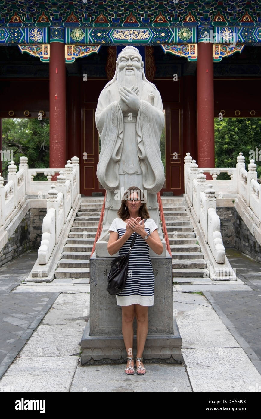 A Woman Stands In Front Of A Statue Of Confucius At The Confucius Temple ; Beijing, China Stock Photo
