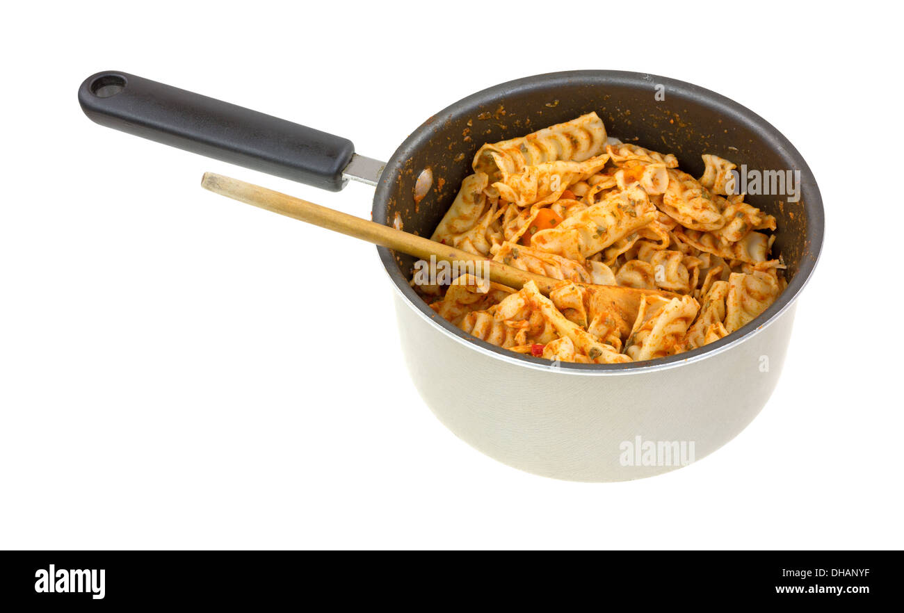 Home made pasta with a tomato sauce in a small saucepan with a wooden spoon on a white background. Stock Photo
