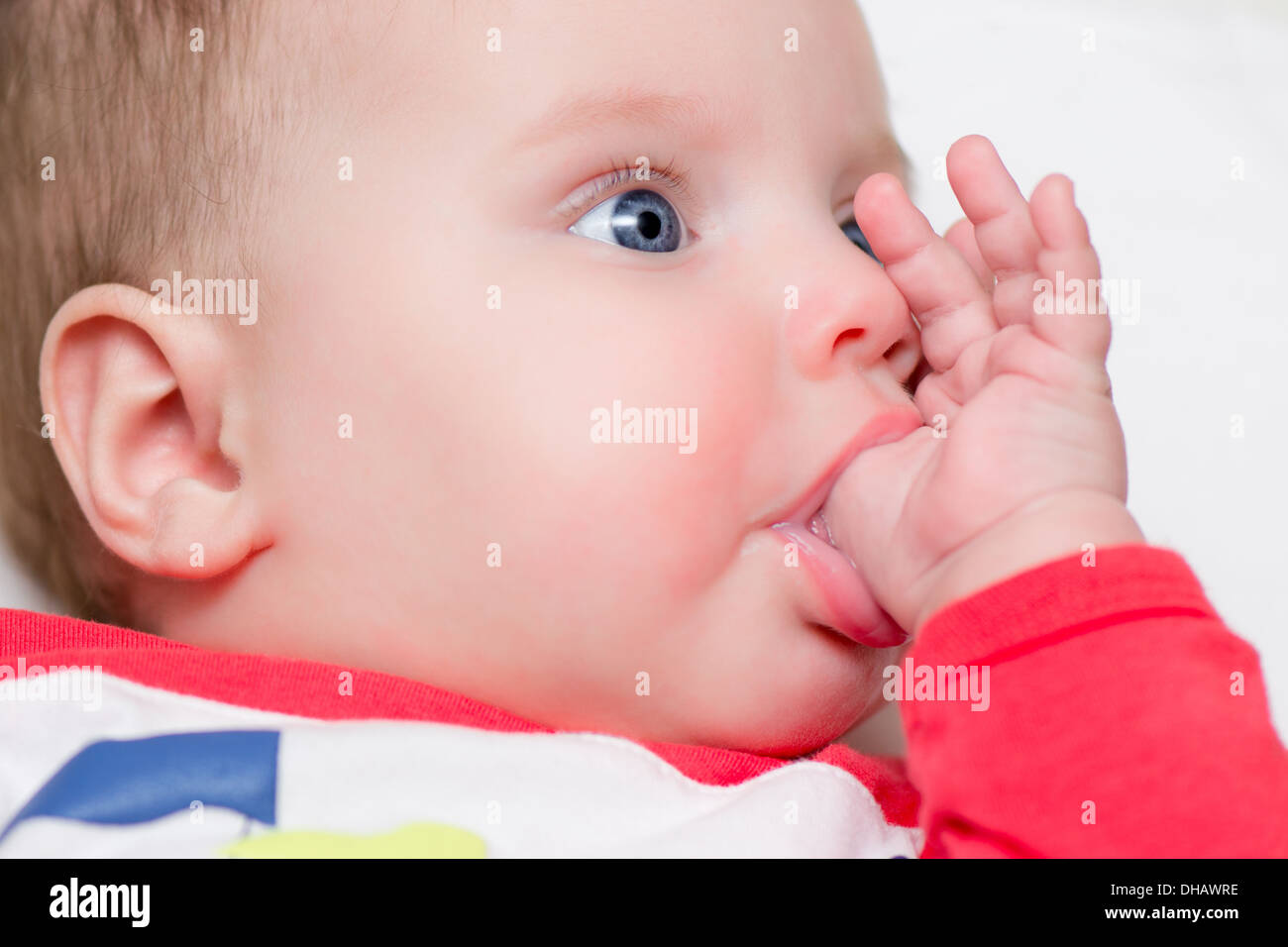 Six months old baby sucking thumb - teething Stock Photo