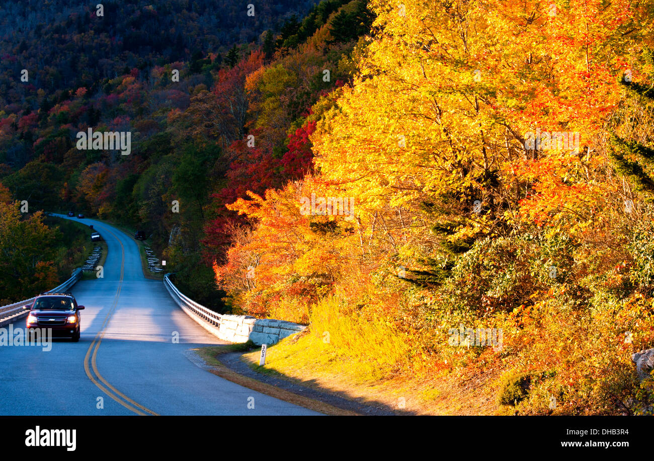 Car with headlights on and autumn color on the Blue Ridge Parkway near the Linn Cove Viaduct in Boone North Carolina Stock Photo