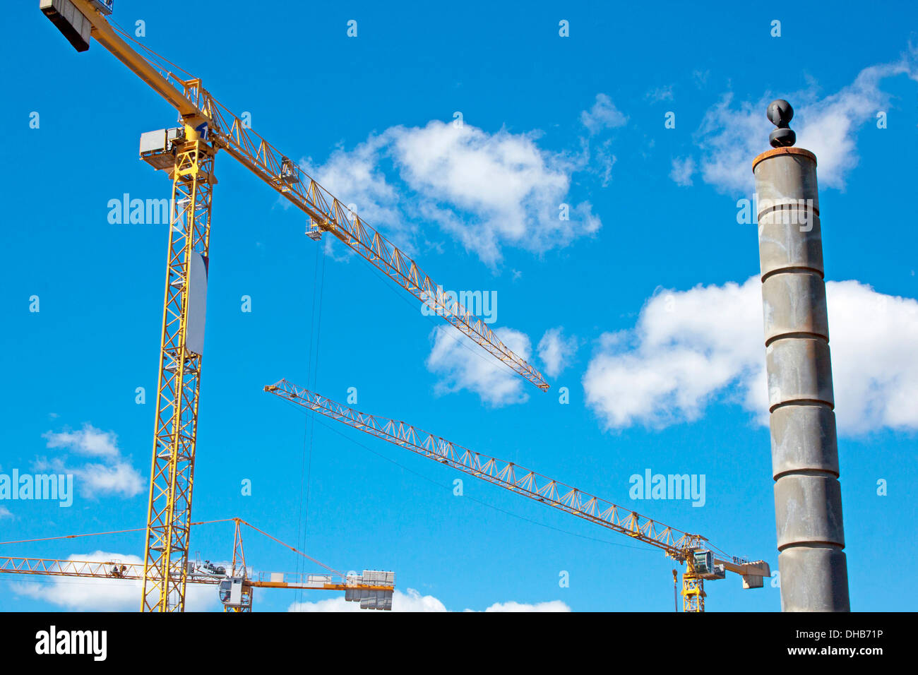 three yellow tower cranes against a clouded skyline Stock Photo