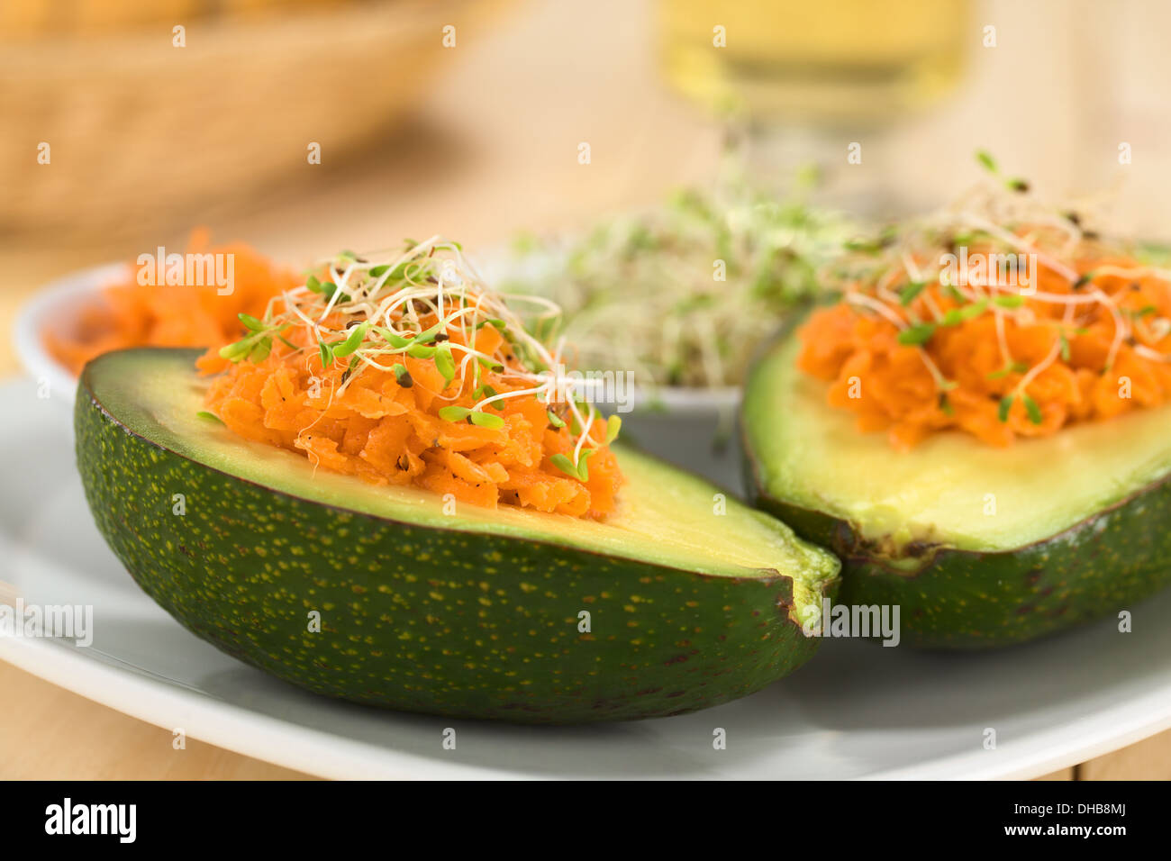 Avocado halves filled with grated carrot and sprinkled with alfalfa sprouts served on plate Stock Photo