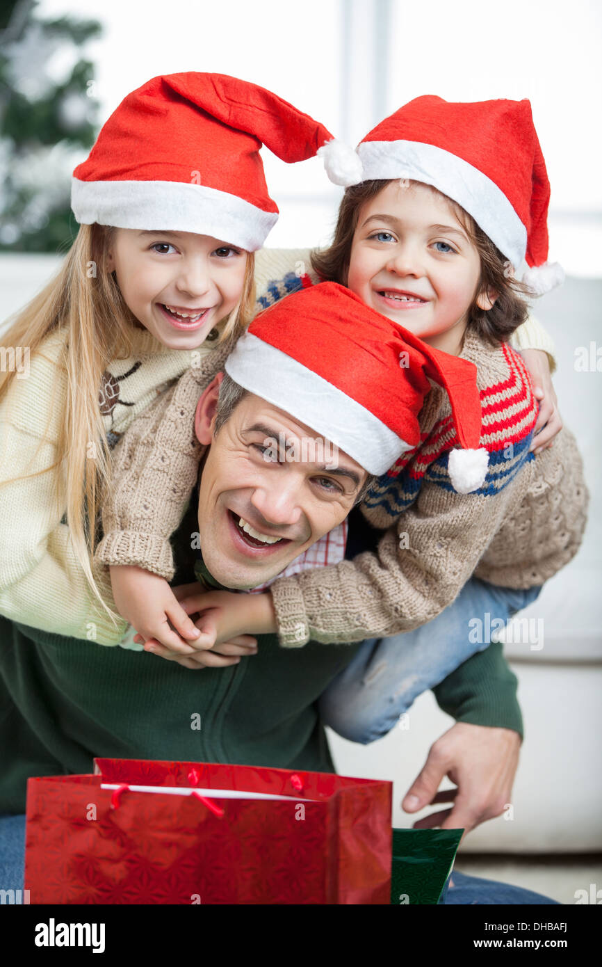 Playful Father Piggybacking Children During Christmas Stock Photo