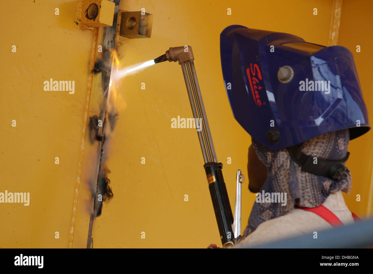 BIA employee using a cutting torch on yellow metal framework, Zambia Stock Photo