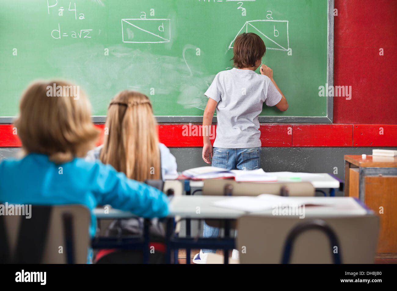 Schoolboy Writing On Greenboard In Classroom Stock Photo - Alamy
