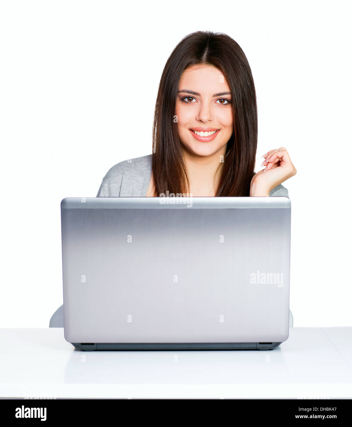 Happy young casual woman sitting at the table with laptop computer ...