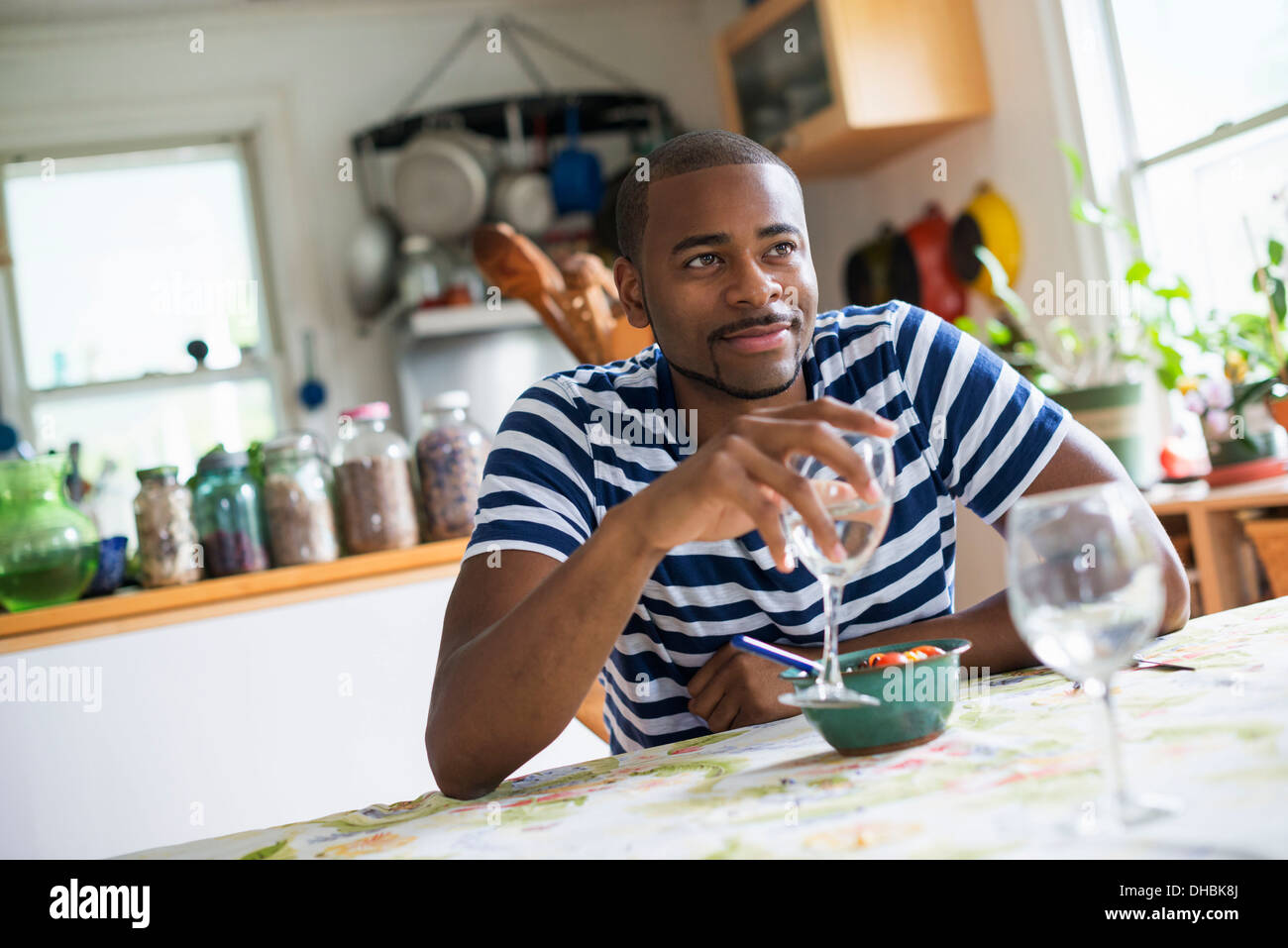 A man sitting at a table eating dessert, holding a glass of wine. Stock Photo