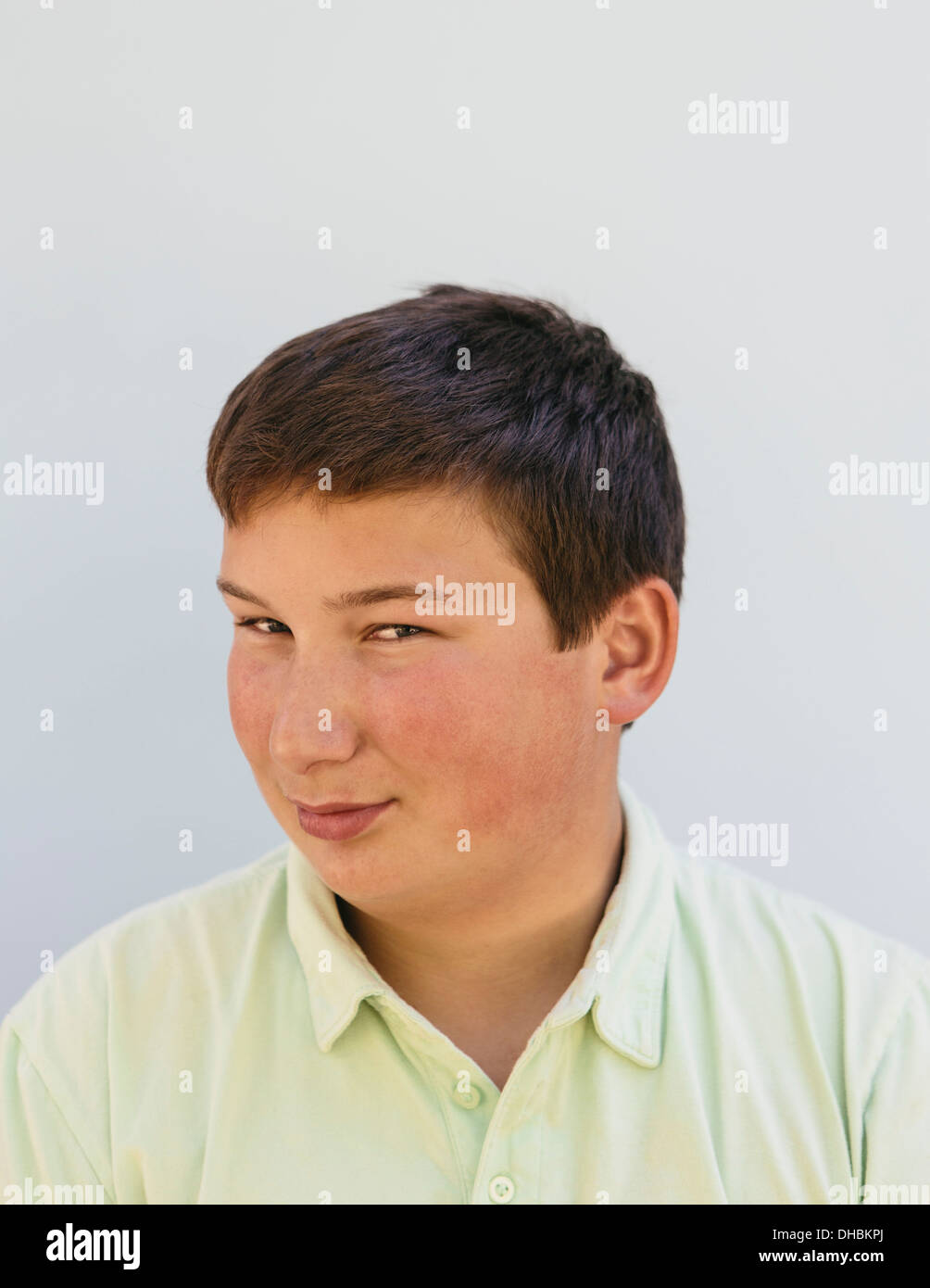 Portrait of a teenage boy with short black hair, looking at the camera and smiling. Stock Photo