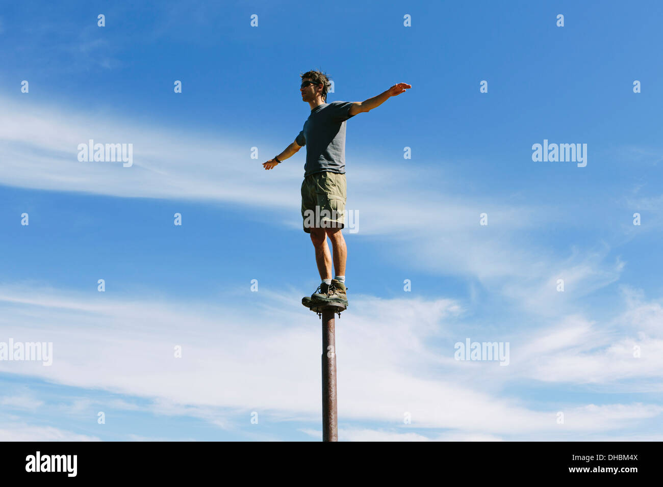 Man standing balancing on metal post looking towards expansive sky on Surprise Mountain Alpine Lakes Wilderness Mt Stock Photo