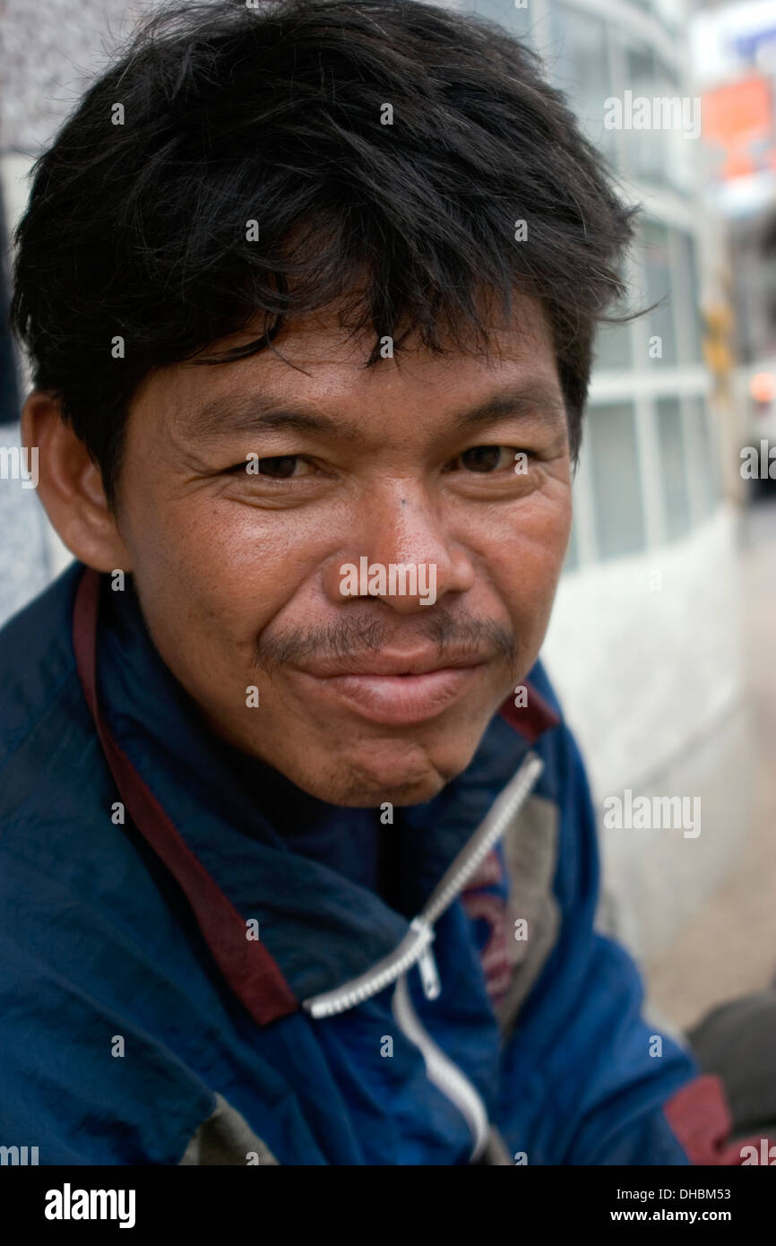A poor homeless man is in need of assistance on a city street in Khorat, Thailand. Stock Photo